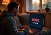 Personne sur un canapé regardant un ordinateur avec logo Netflix et VPN