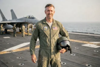 Pilote de chasse en combinaison de vol sur le pont d'un porte-avions, évoquant l'univers de Top Gun 3
